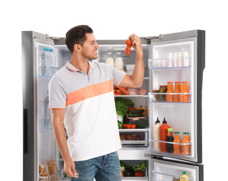 Man with tomatoes near open refrigerator on white background