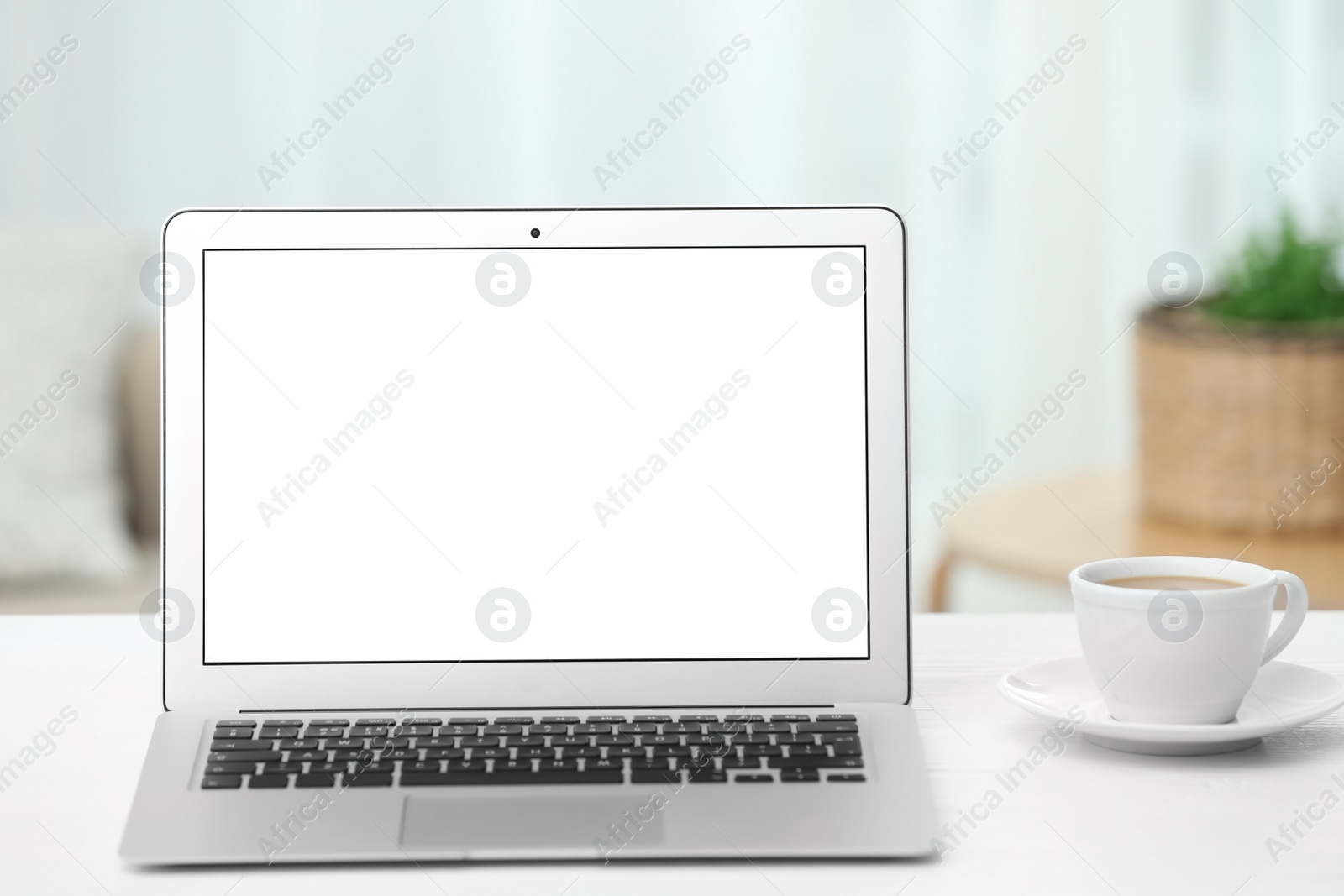 Photo of Laptop with blank screen on table indoors. Space for text