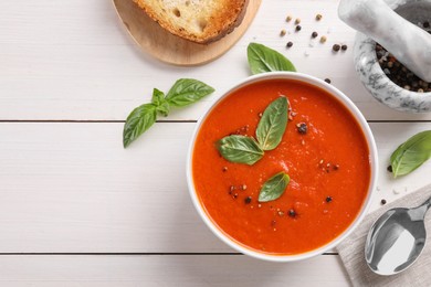 Photo of Flat lay composition with delicious tomato cream soup in bowl on white wooden table. Space for text