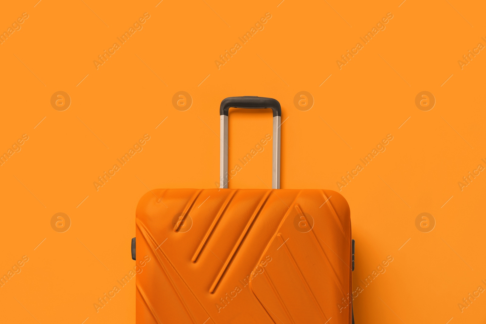 Image of Stylish bright suitcase on orange background, top view