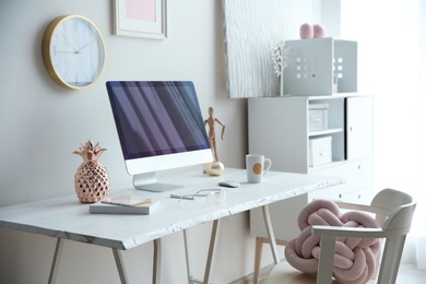 Photo of Contemporary workplace with computer on table near white wall. Interior design