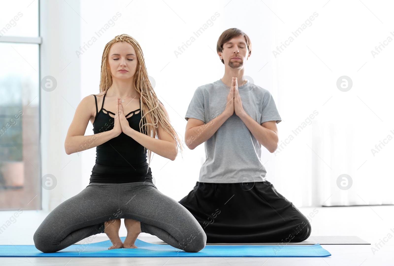 Photo of Young man and woman practicing yoga indoors