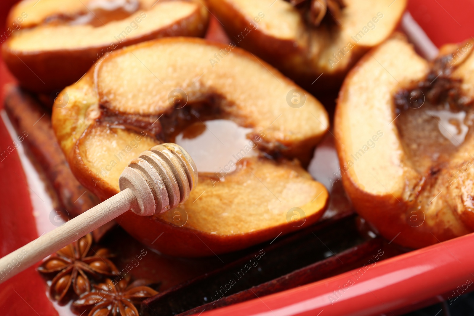 Photo of Pouring tasty honey onto baked quinces in dish, closeup