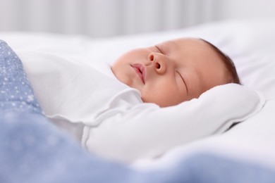 Photo of Cute newborn baby sleeping under blue blanket on bed, closeup