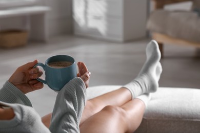 Photo of Woman with cup of aromatic coffee relaxing at home, closeup