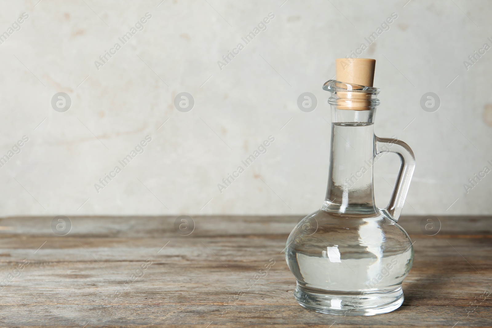 Photo of Glass jug with vinegar on table. Space for text