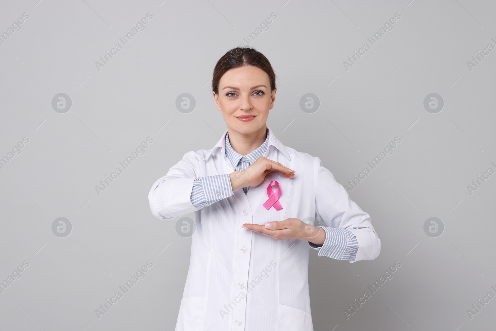 Photo of Mammologist with pink ribbon on grey background. Breast cancer awareness
