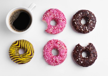 Tasty donuts and cup of coffee on white background, flat lay