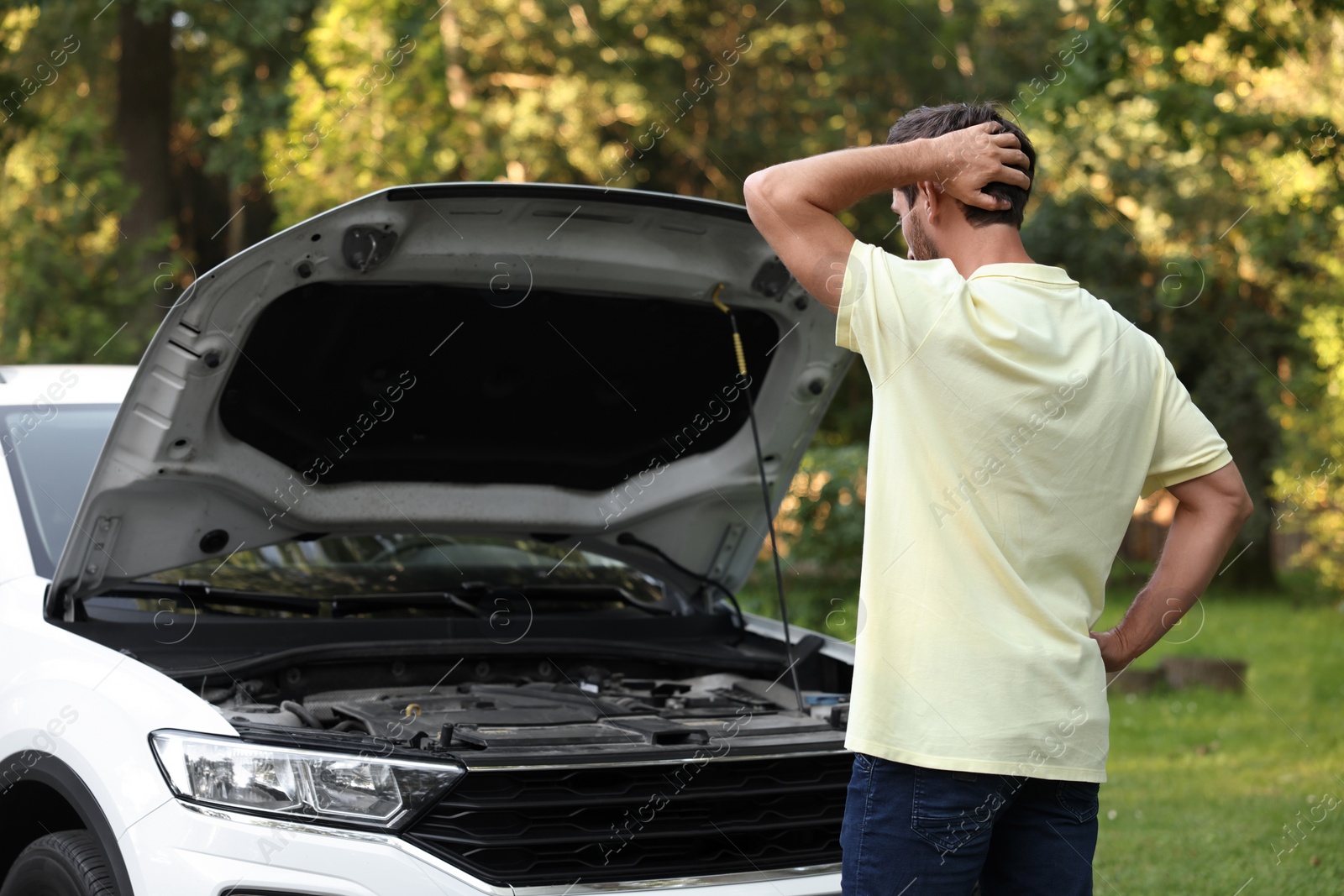 Photo of Man looking under hood of broken car outdoors