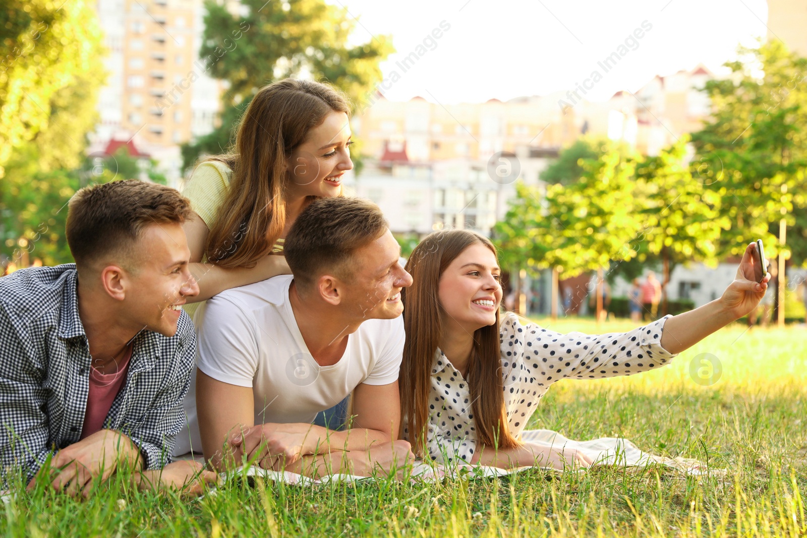 Photo of Young people taking selfie while having picnic in park on summer day