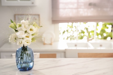 Photo of Bouquet of beautiful eustoma flowers on white table in kitchen. Interior design