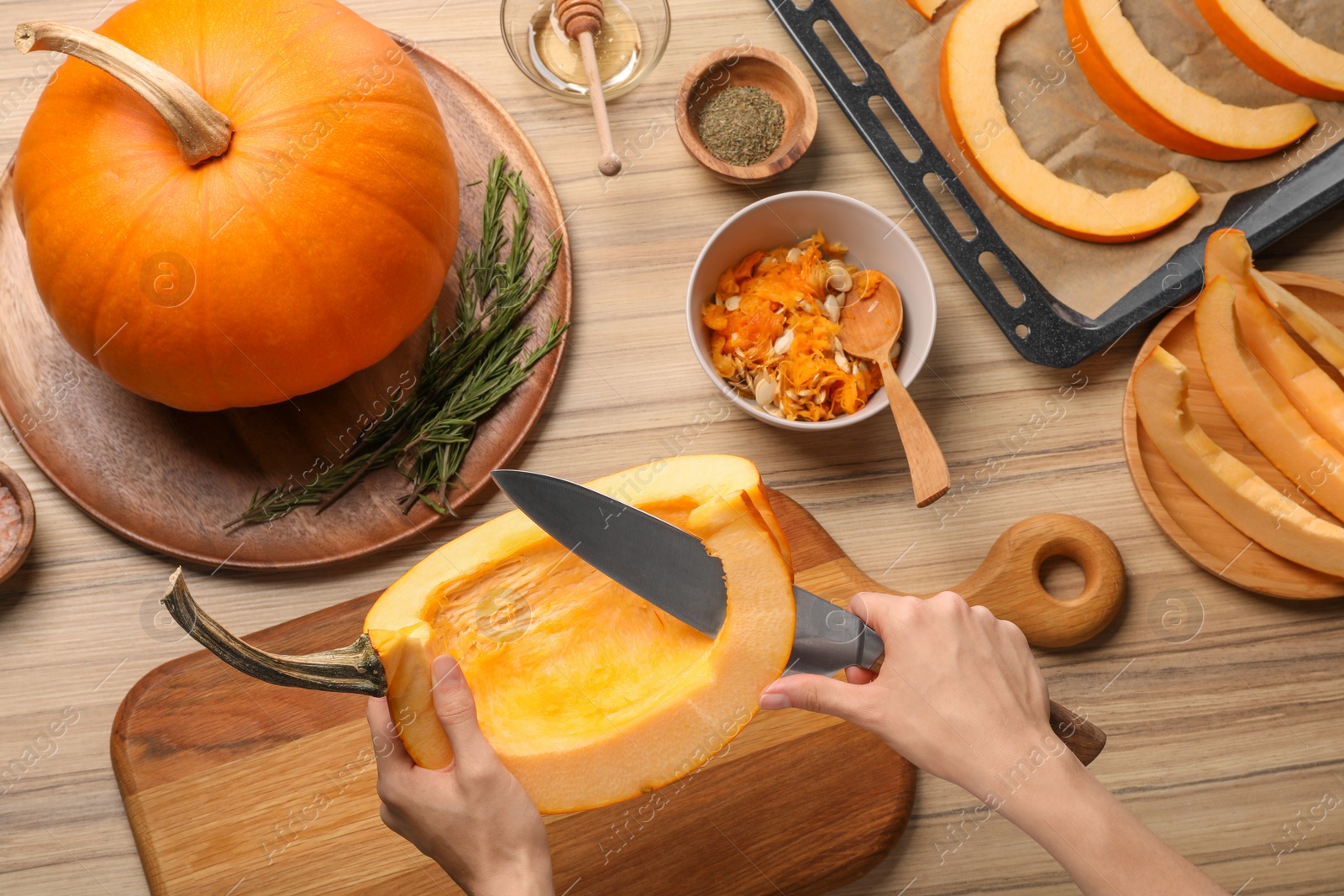 Photo of Woman slicing fresh pumpkin at wooden table, top view