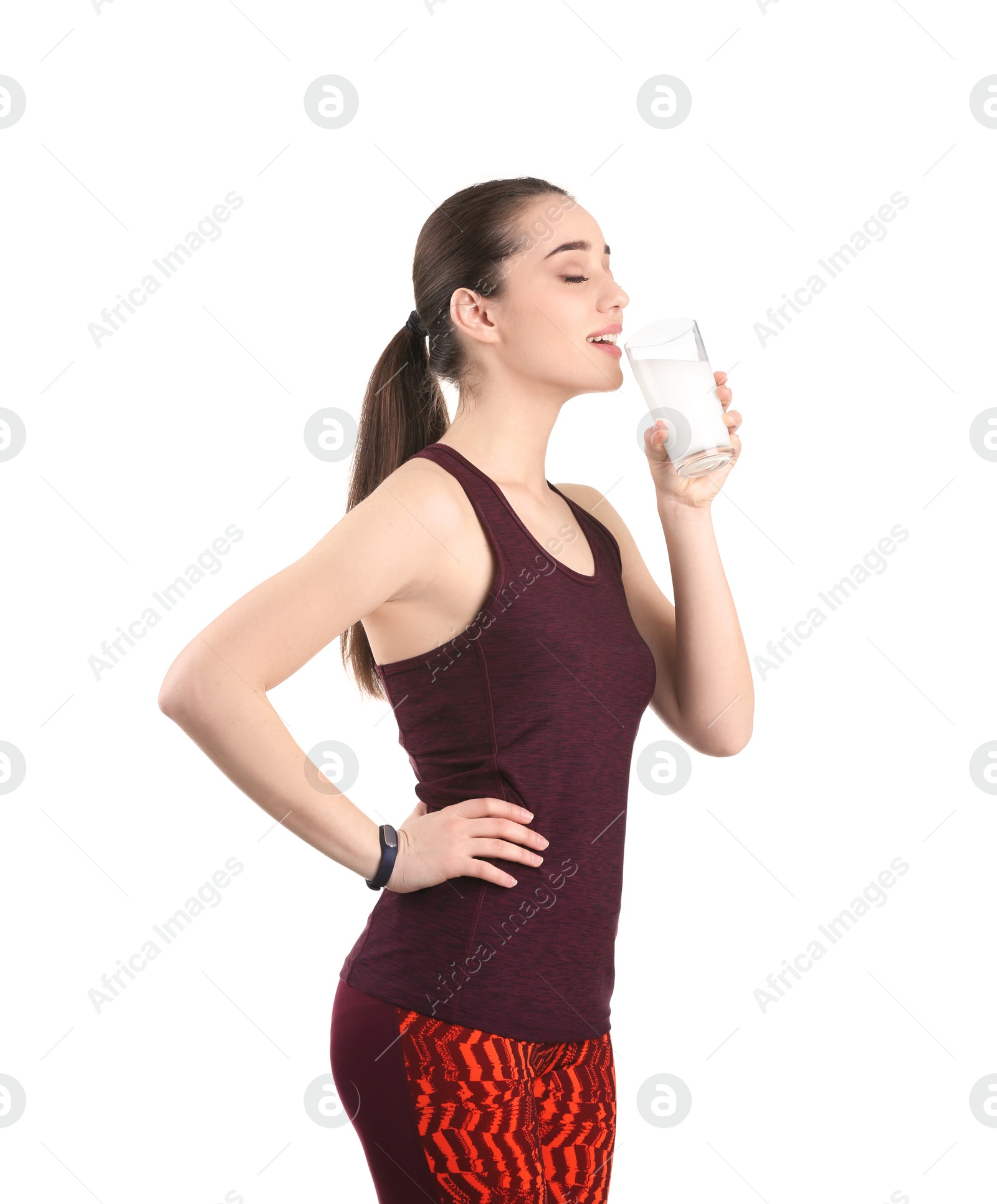 Photo of Beautiful young woman in sportswear drinking milk on white background