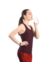 Beautiful young woman in sportswear drinking milk on white background