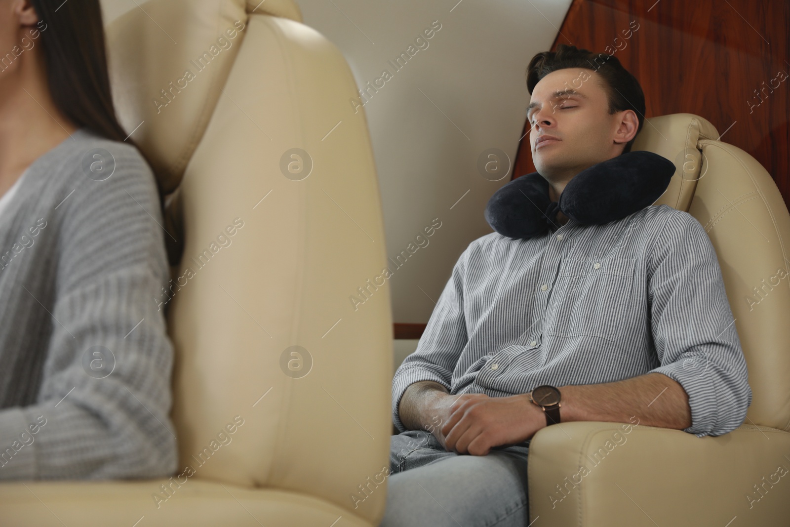Photo of Young man with travel pillow sleeping in airplane during flight