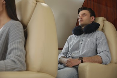 Photo of Young man with travel pillow sleeping in airplane during flight