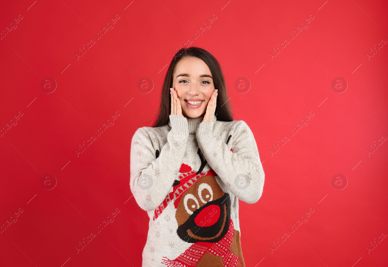 Photo of Young woman in Christmas sweater on red background