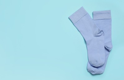 Pair of new socks on light blue background, top view. Space for text
