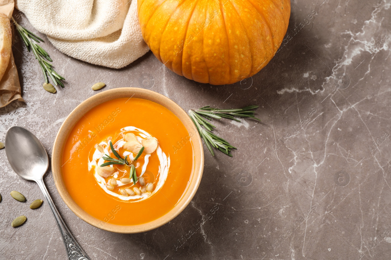 Photo of Delicious pumpkin soup in bowl on marble table, flat lay. Space for text