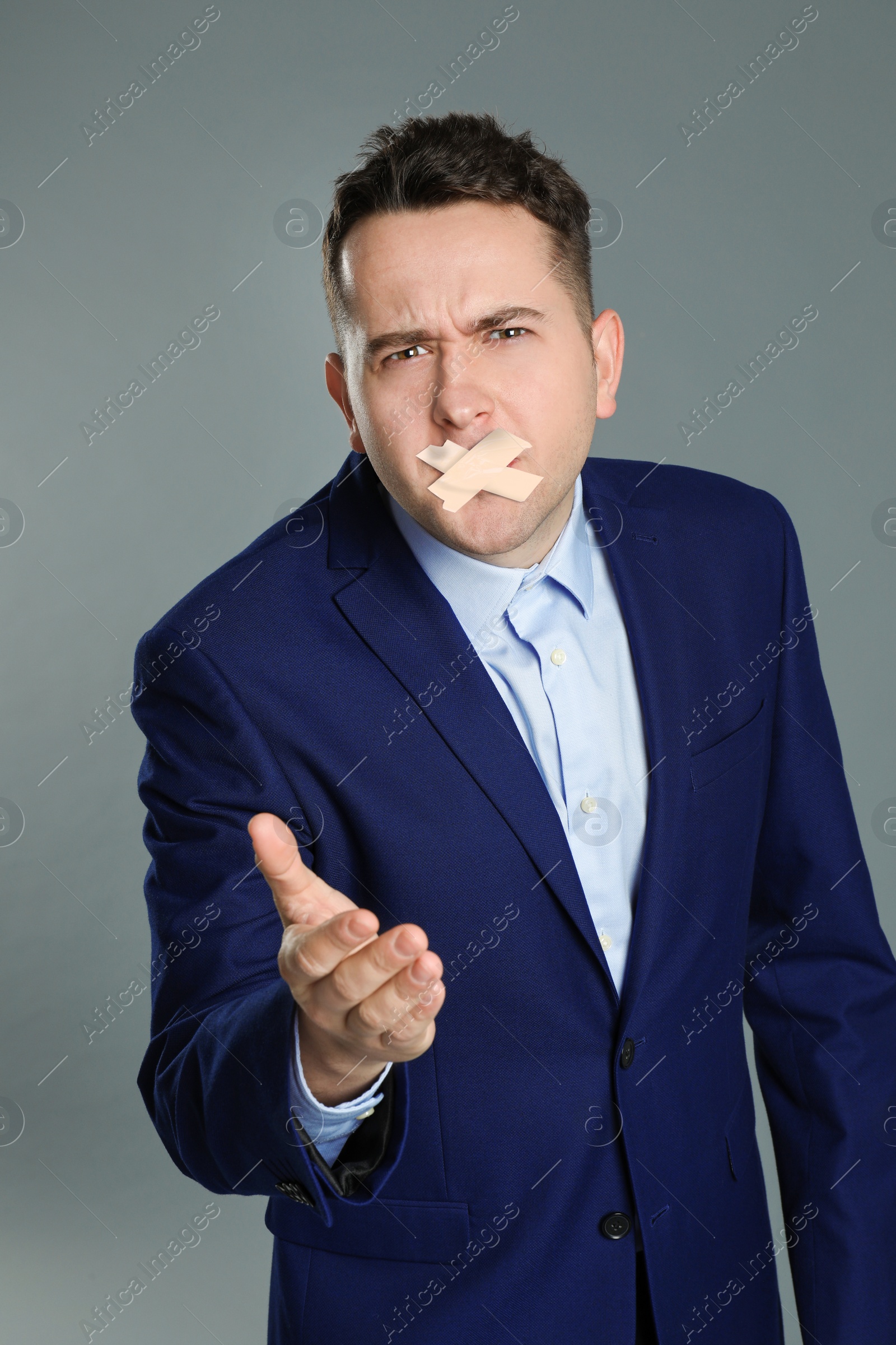 Image of Man with taped mouth on grey background. Speech censorship