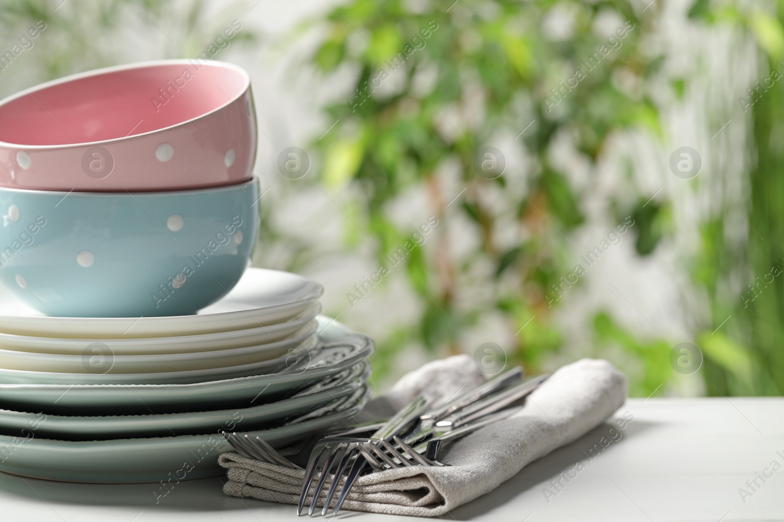 Photo of Beautiful ceramic dishware and cutlery on white table outdoors, space for text