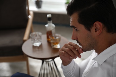 Photo of Man near table with whiskey at home. Space for text
