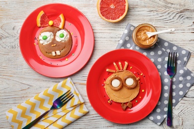 Photo of Funny pancakes for kids breakfast on wooden table, top view