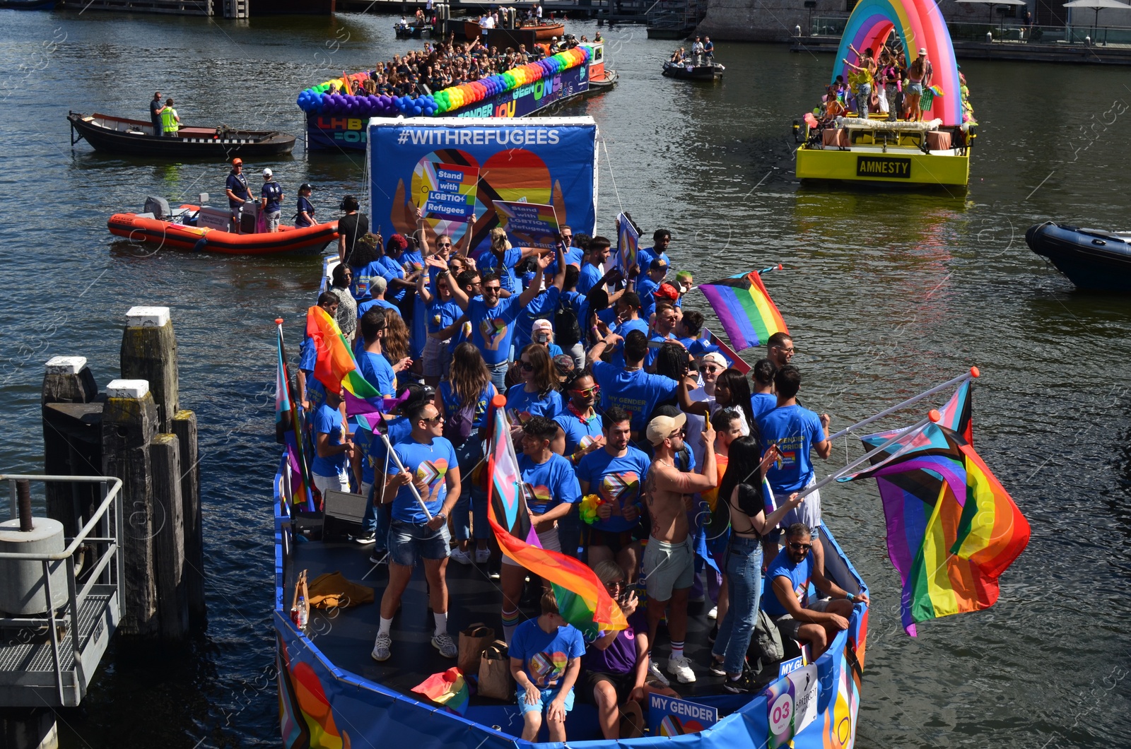 Photo of AMSTERDAM, NETHERLANDS - AUGUST 06, 2022: Many people in boats at LGBT pride parade on river