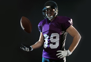 American football player with ball on dark background