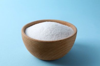 Photo of Organic white salt in bowl on light blue background