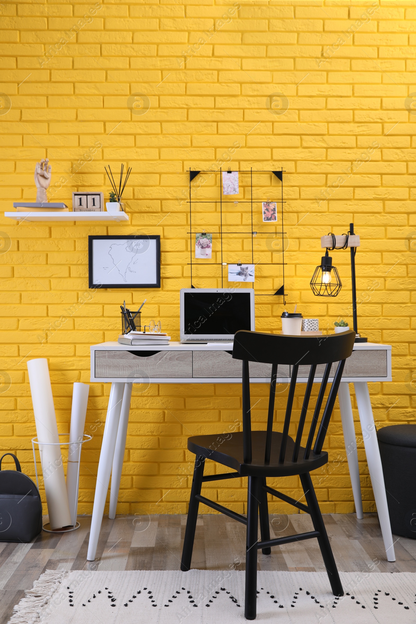 Photo of Stylish home office interior with comfortable workplace near yellow brick wall