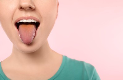 Photo of Gastrointestinal diseases. Woman showing her yellow tongue on pink background, closeup. Space for text