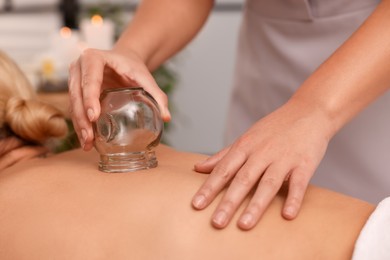 Photo of Therapist giving cupping treatment to patient indoors, closeup