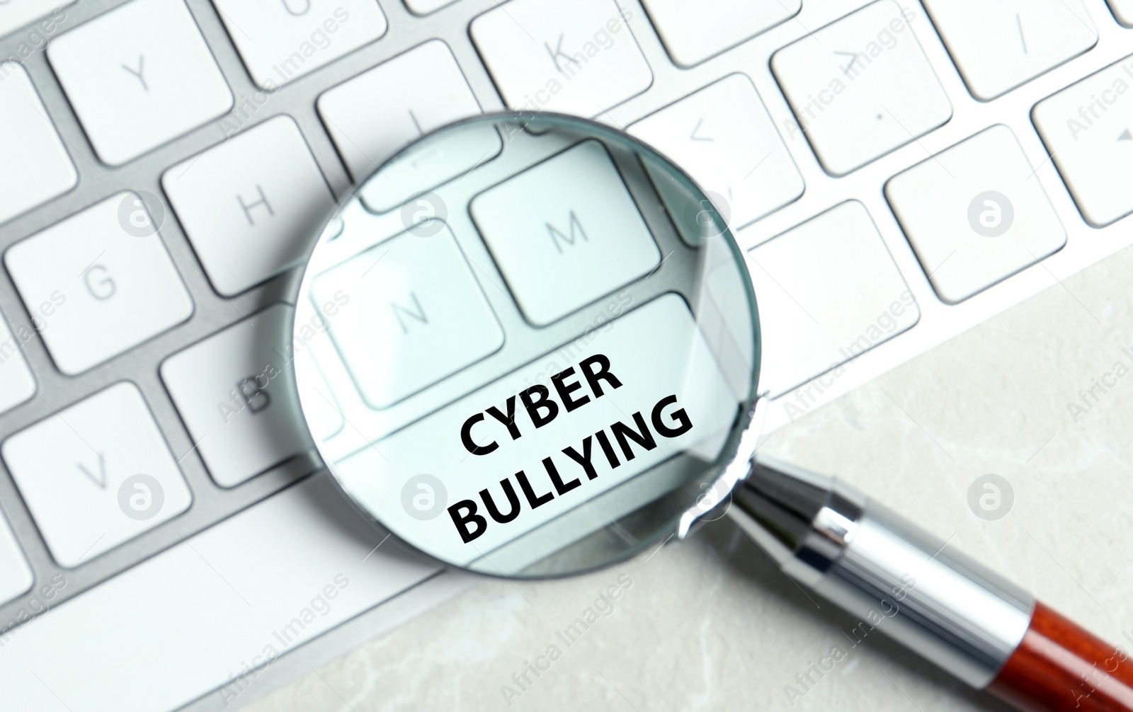 Image of Magnifying glass and computer keyboard with phrase CYBER BULLYING on white button, top view