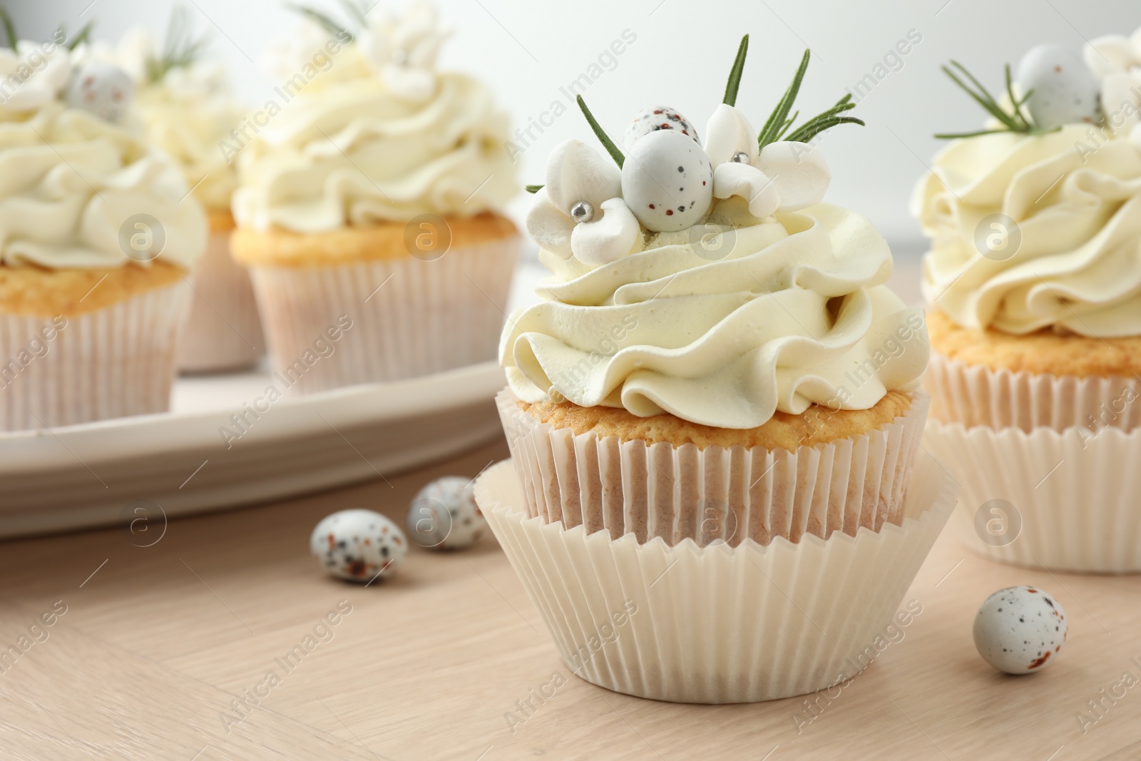 Photo of Tasty Easter cupcakes with vanilla cream on wooden table, closeup