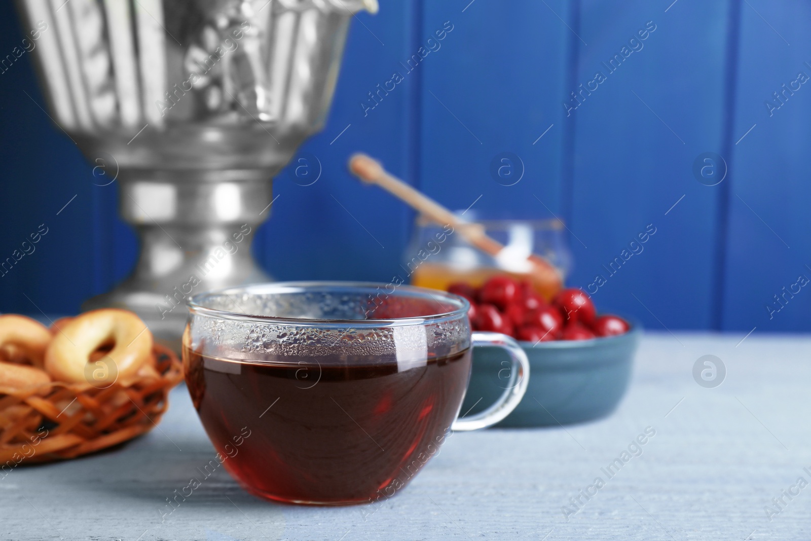 Photo of Glass cup of aromatic tea on light blue wooden table