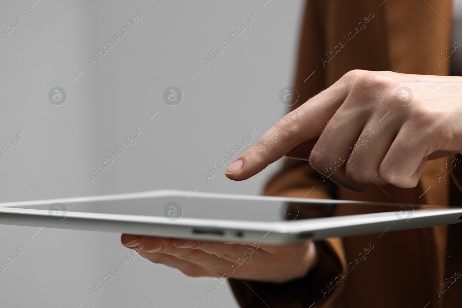 Photo of Closeup view of woman using modern tablet on grey background