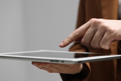 Closeup view of woman using modern tablet on grey background