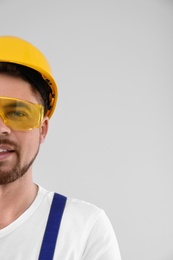 Photo of Male industrial worker in uniform on light background, space for text. Safety equipment