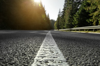 Photo of Closeup view of asphalt road surrounded by forest on sunny day