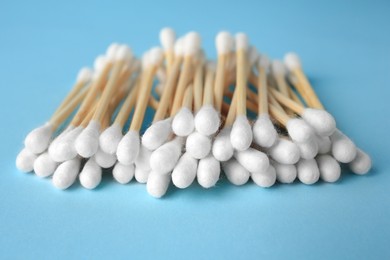 Heap of clean cotton buds on light blue background