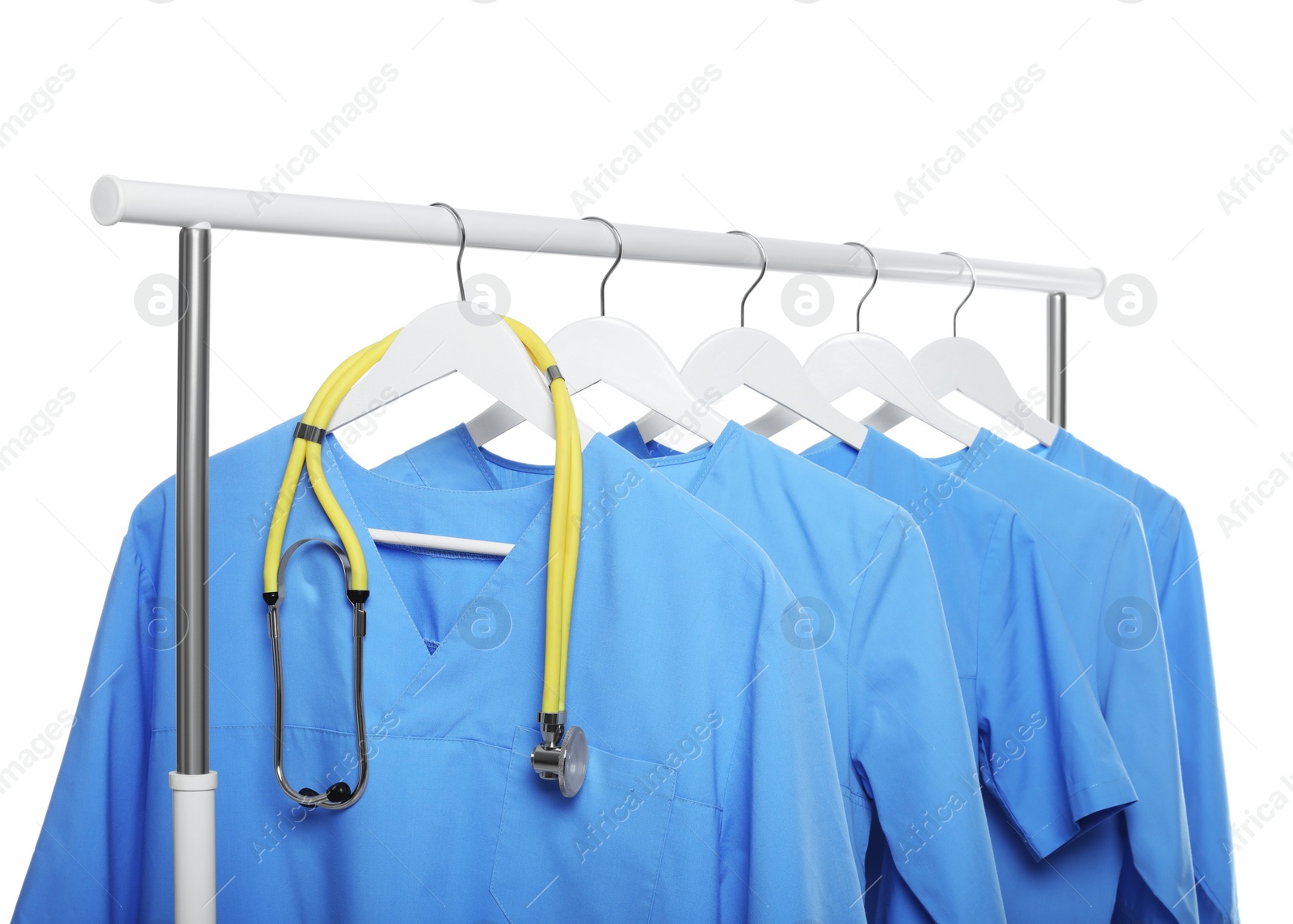 Photo of Light blue medical uniforms and stethoscope on rack against white background