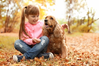 Photo of Cute little girl with her pet in park. Autumn walk