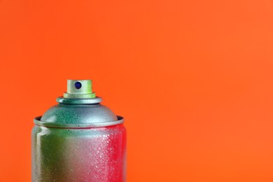 Photo of Used can of spray paint on orange background, closeup. Space for text