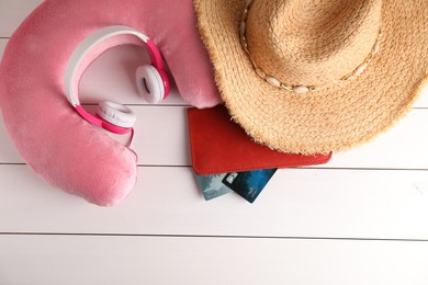 Photo of Pink travel pillow, hat, headphones and wallet with credit cards on white wooden background, flat lay. Space for text