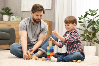 Photo of Dad and son building tower with cubes at home