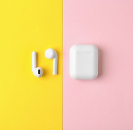 Photo of Modern wireless earphones and charging case on color background, flat lay