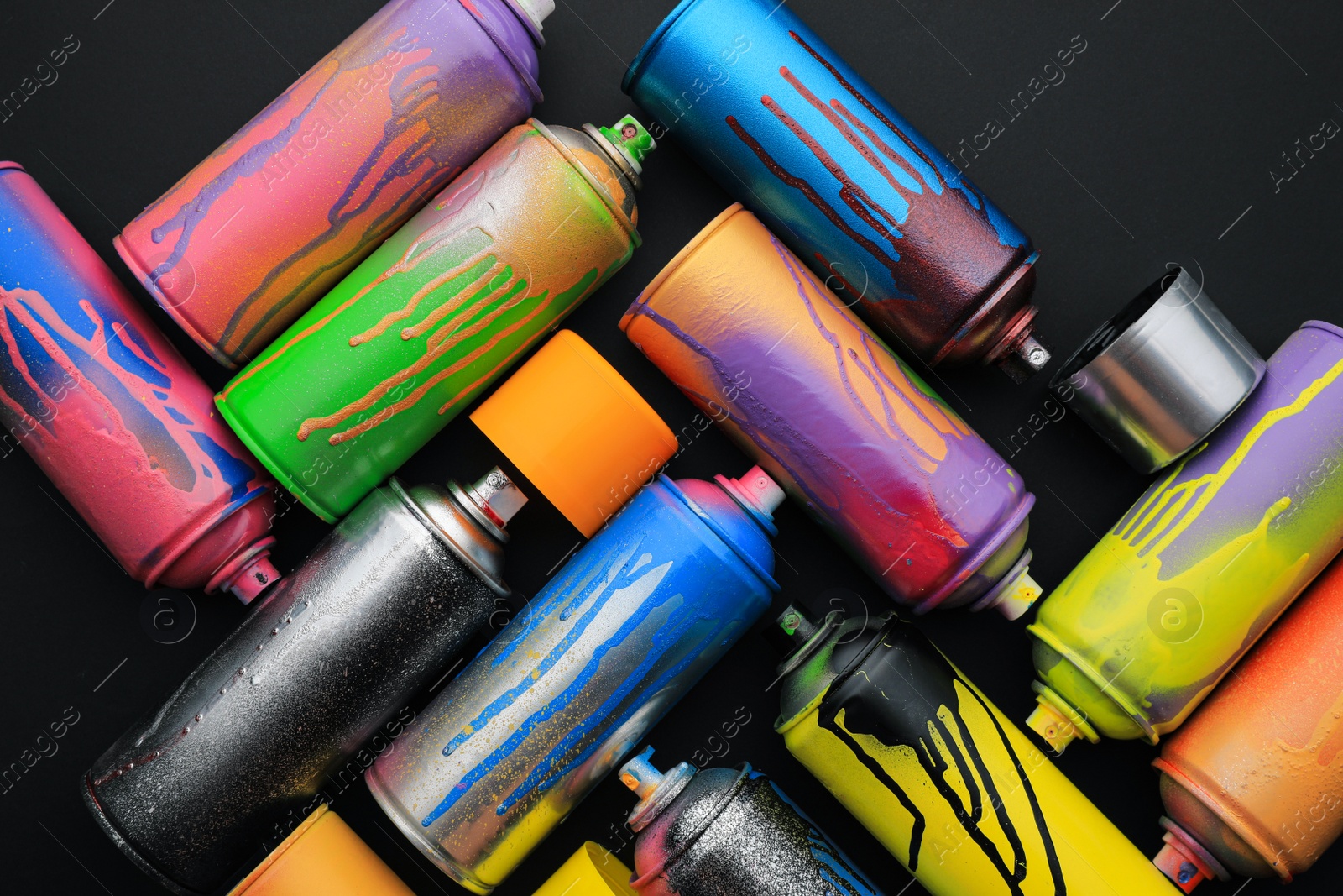 Photo of Used cans of spray paints on black background, flat lay. Graffiti supplies