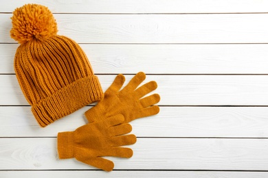 Photo of Stylish gloves and hat on white wooden background, flat lay. Space for text