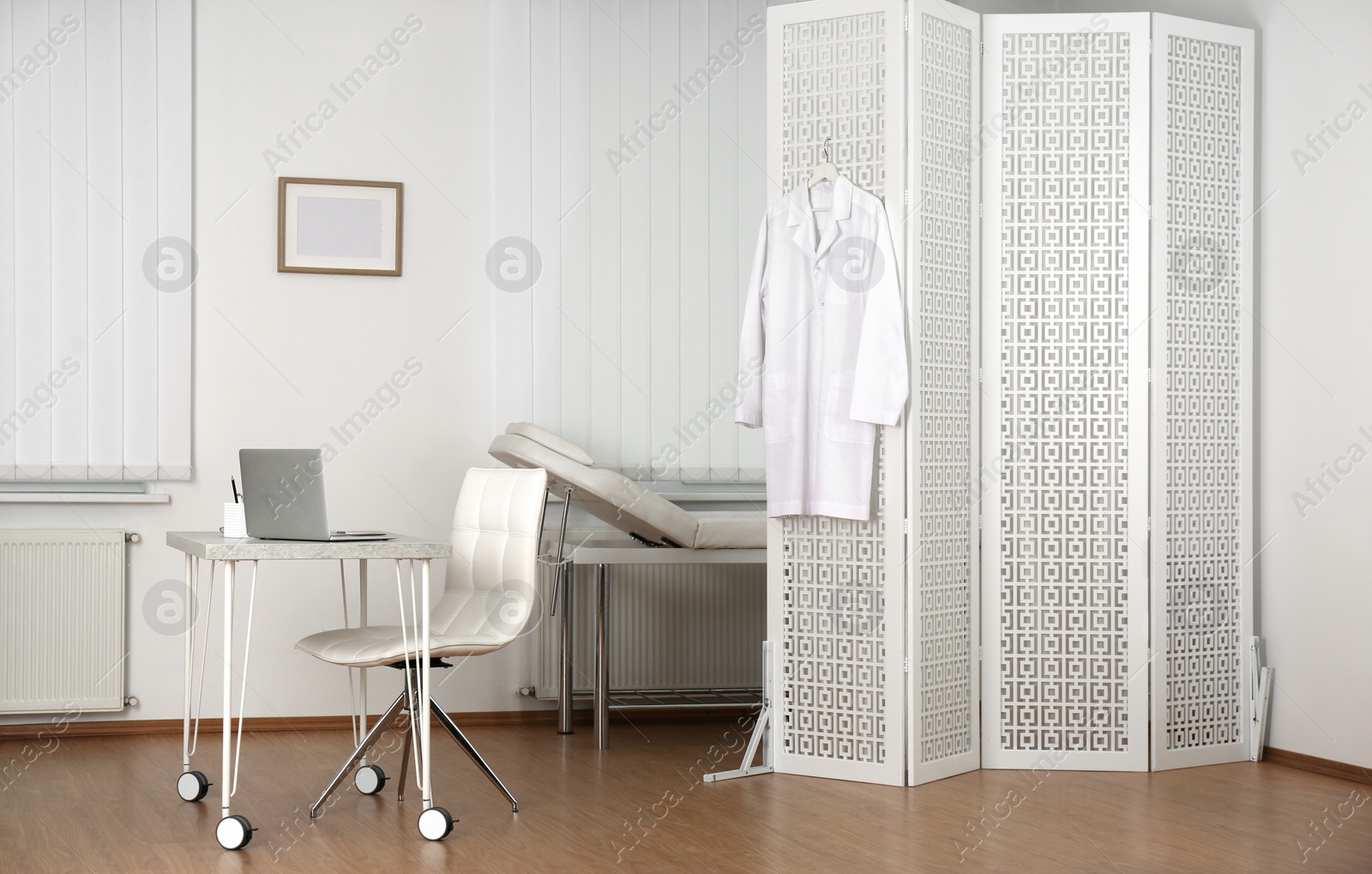 Photo of Doctor's office interior with desk, examination couch and folding screen